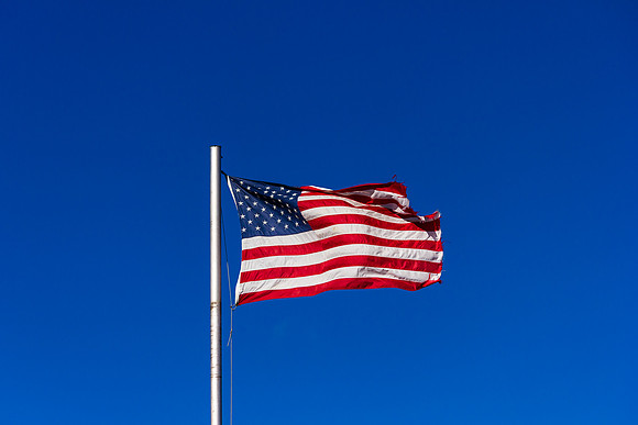 American Flag in high wind on blue sky