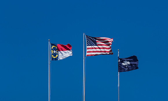 U.S., N.C. and S.C. Flags against clear blue sky